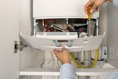 Heating technician repairing a residential boiler in El Monte