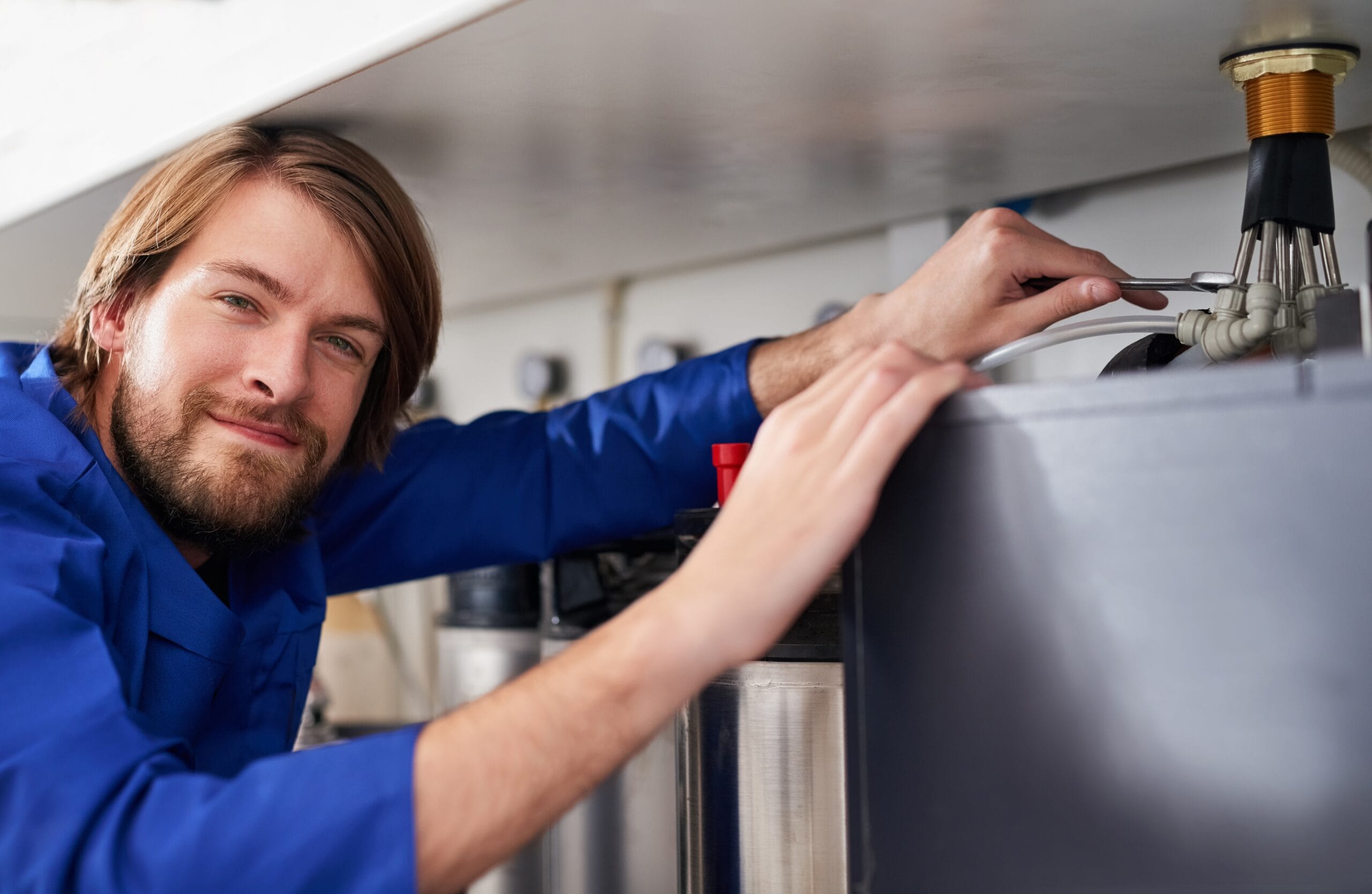 Technician servicing a residential water heater tank in El Monte